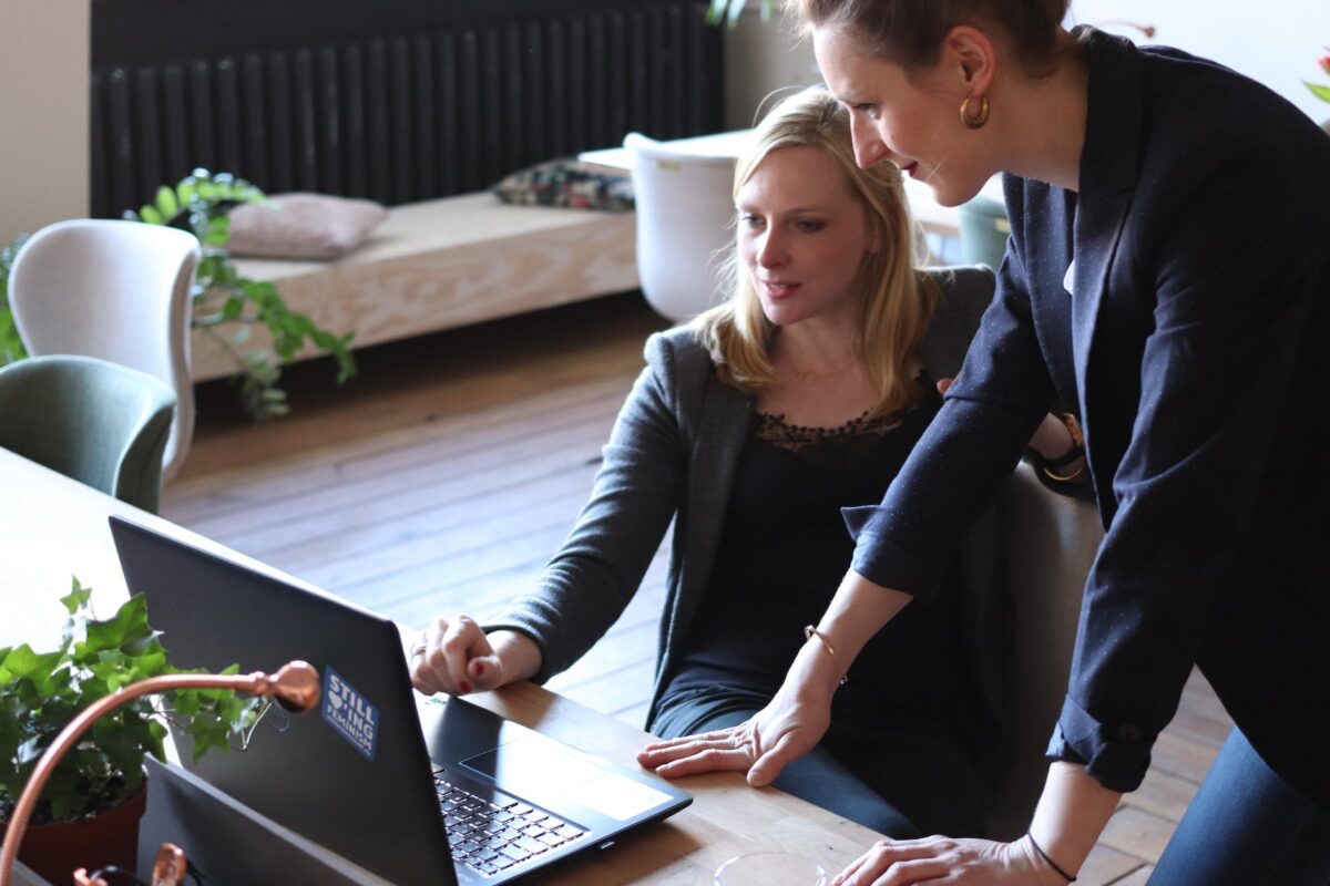 two women using on black laptop computer