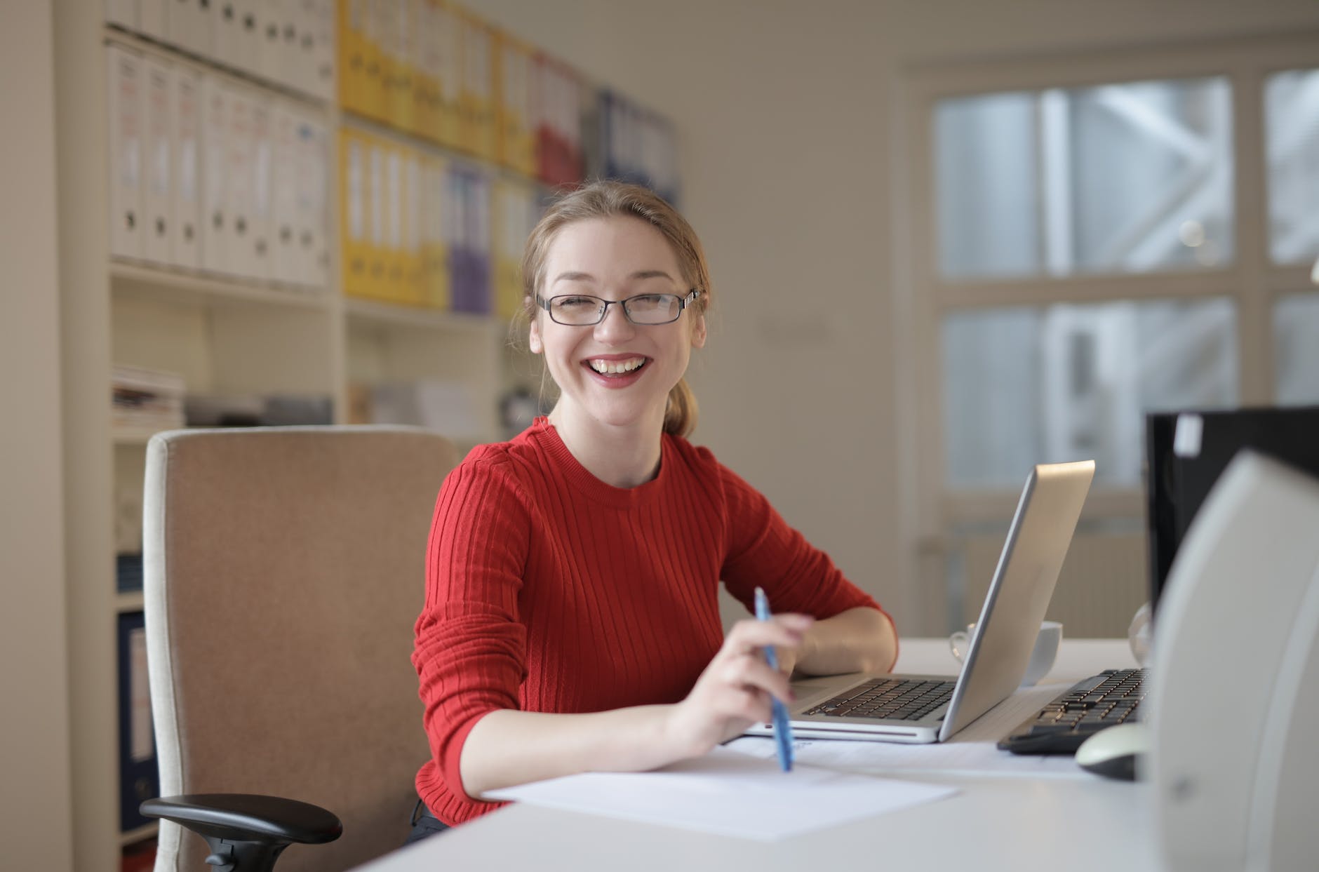 woman in red sweater leaning on white table