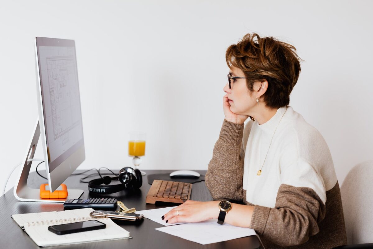 thoughtful architect in eyeglasses studying building plan on computer screen