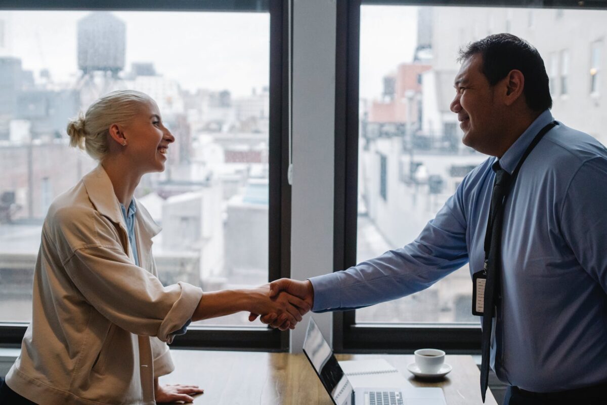 cheerful colleagues shaking hands while standing at table