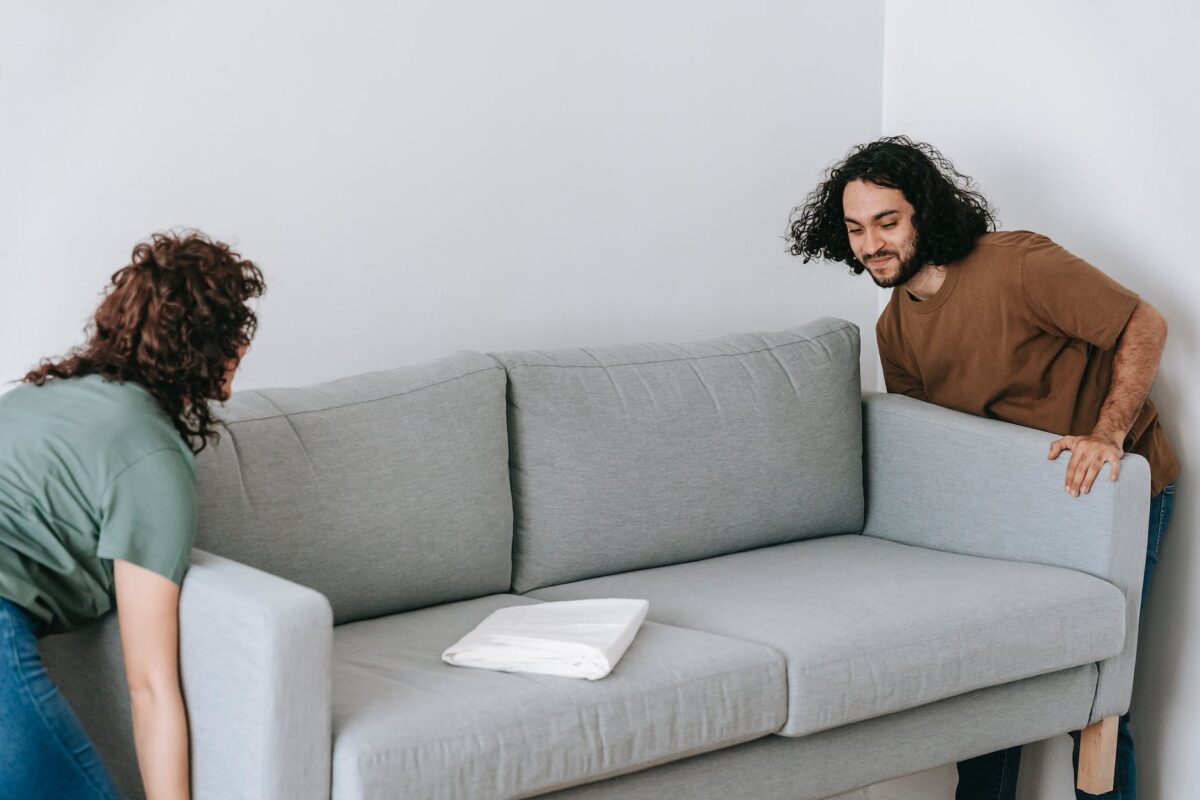 couple moving sofa in room