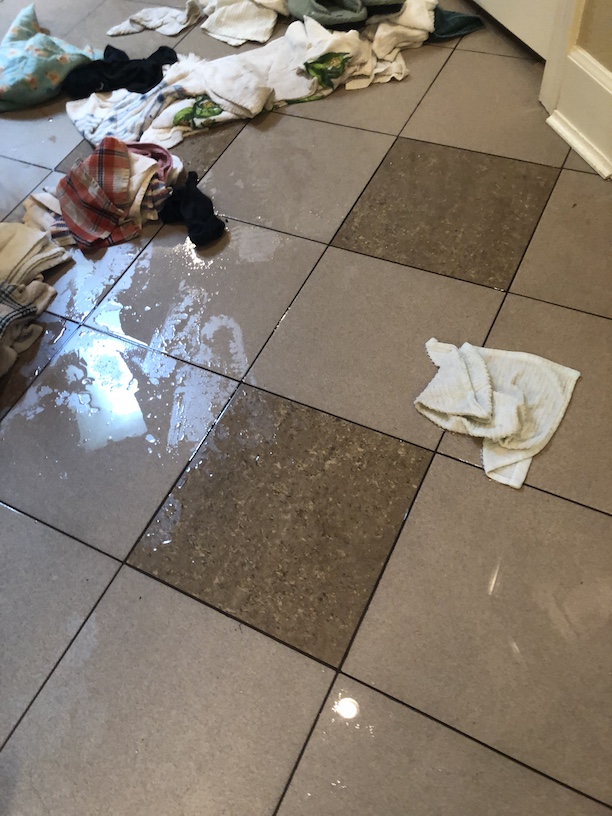 Image of a wet tile floor from a water damage with dirty wet towels strewn about in Vancouver WA