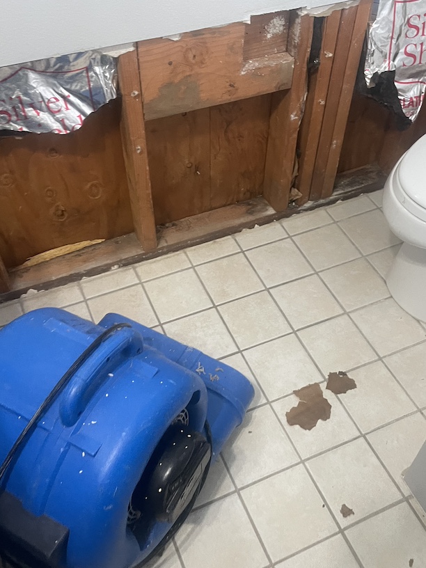 An air mover blowing dry air onto the exposed stud bays near the toilet that caused the water damage