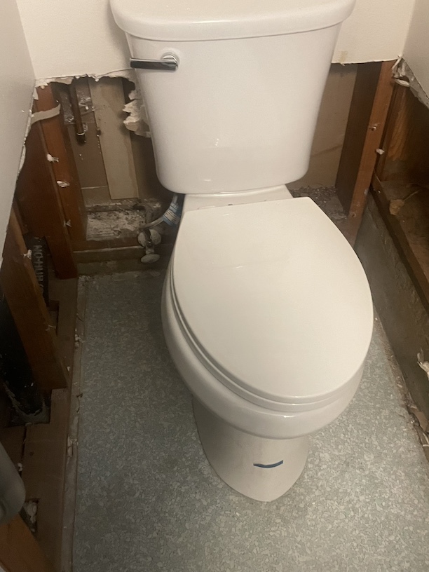 Bathroom toilet with drywall removed behind it.